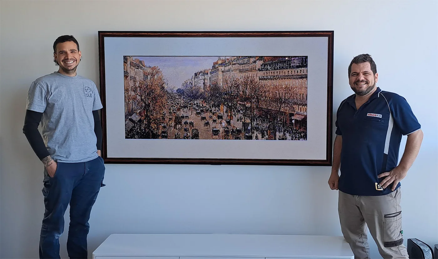 Two people standing beside a wall-mounted television, from the TV Mount Australia website